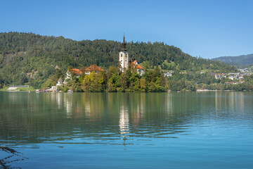 Fototapeta premium Pilgrimage Church of the Assumption of Mary (Bled Island Church). Bled Island. Stunning Panoramic View of Lake Bled with Iconic Island and Castle, Slovenia. Romantic spot. Water reflection.