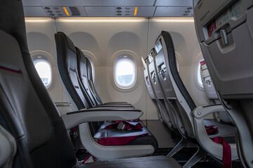 An interior view of an airplane showcasing rows of comfortable seats and large windows, ideal for travelers seeking a comfortable flying experience in modern aviation.