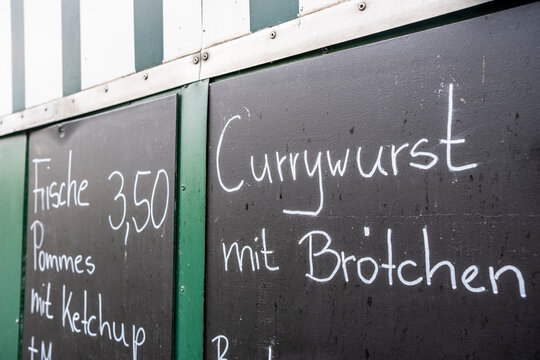 A chalkboard menu lists popular food items, specifically highlighting currywurst, inviting food lovers to indulge in delicious local culinary delights.