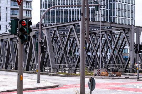 The image features a steel bridge along with traffic signals, portraying the complexity of urban infrastructure and the daily life rhythms of a bustling city.
