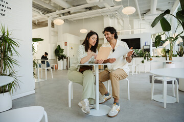 Woman points at menu and talks while man listens and smiles as they sit at table