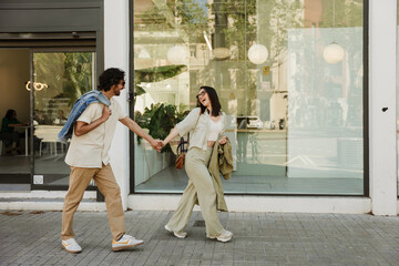 A man follows a woman while they laugh and hold hands