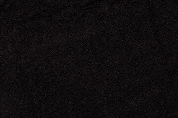 Fine black charcoal powder texture captured in close-up detail, showing natural particles and organic surface suitable for cosmetic