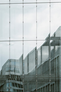 A serene view of a building's facade reflecting neighboring structures, providing a captivating snapshot of urban architecture blended with reflective glass.