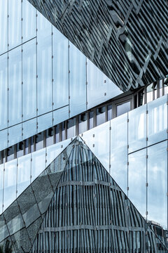 An architectural marvel showcases layered glass in an intriguing design, reflecting the surrounding environment and exhibiting modern artistic sensibilities.
