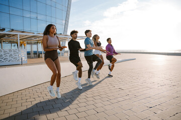 A group of five athletes run in place, side by side, holding their hands in front of them