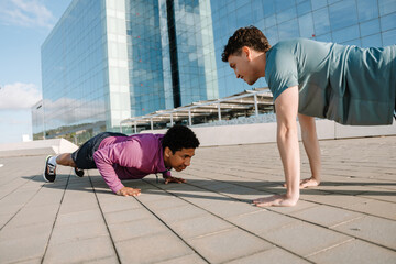 Two male athletes doing push-ups from the ground facing each other