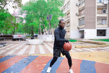 Young Man Dribbling Basketball Outdoors in Springtime.
