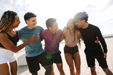 Fototapeta premium A group of five athletes hug and laugh as they walk in a row