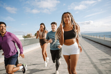 A female athlete runs next to a group of three athletes while two of them laugh