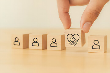 Hand adding wooden block with handshake and heart symbol, building team unity and partnership, a modern approach to business networking concept