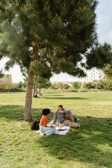 Male student talking to female student while they sit on a blanket