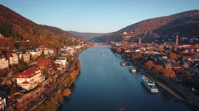 Drone Tracking Shot of Rowing Team and River Cruise Ships on the Neckar River with Heidelberg Castle and Old Bridge in Autumn