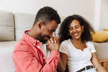 Obraz premium A man kisses the hand of a woman sitting next to him and smiles with her eyes closed as they hold hands and lean on the sofa