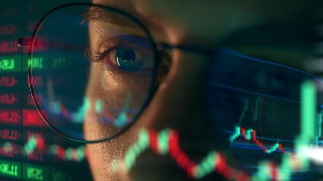 Trader wearing glasses is working on laptop computer. Screen with stock market charts and Bitcoin BTC or Ethereum ETH data analysis reflection. Broker trading online. Altcoins crypto currency trading