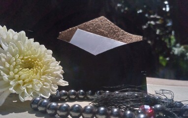 White Flowers with Prayer Beads and Elegant Envelope on Wooden Table &ndash; Natural Light 