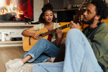 Female musician singing and sitting on the floor with male musician while they play guitars