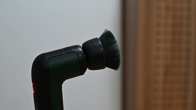 Handheld electric scrubbing brush running continuously, creating a high-pitched motor whirring and repetitive brush spinning sound.
