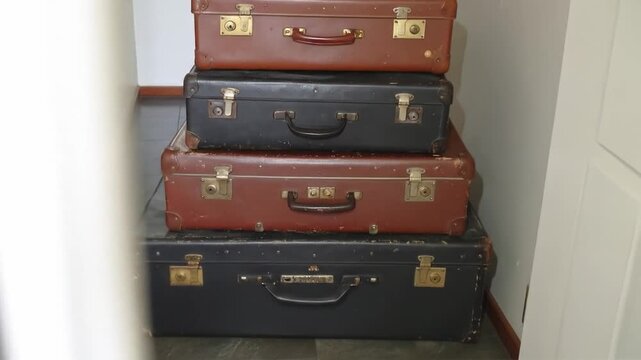Stacked vintage suitcases in indoor setting with wooden door