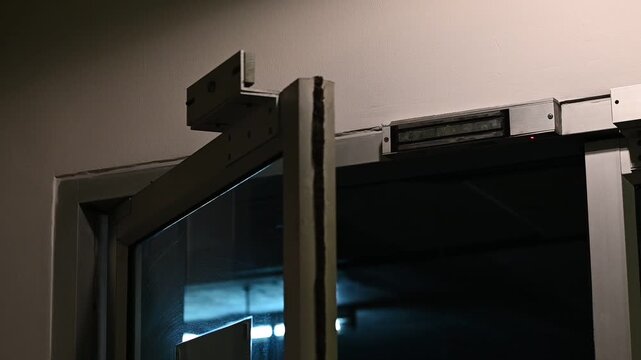 Public aluminum door magnetic lock engaging, creating a sharp electromagnetic thump, loud mechanical click sound and beeping sound.