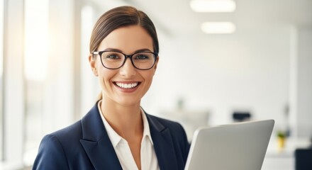 Headshot of a cheerful professional woman in glasses with a laptop in a bright office