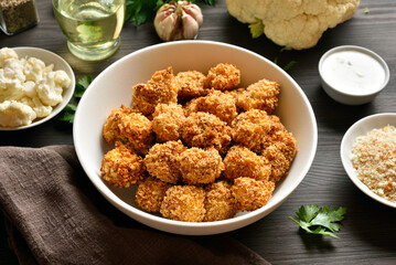 Breaded oven baked cauliflower bites in bowl on wooden table