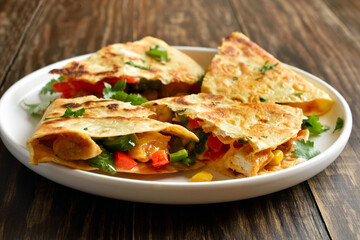 Chicken quesadilla with fresh vegetables on wooden table