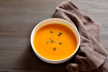 Delicious pumpkin and carrot soup in white bowl