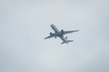 Big white passenger airplane landing over the head on a grey overcast day