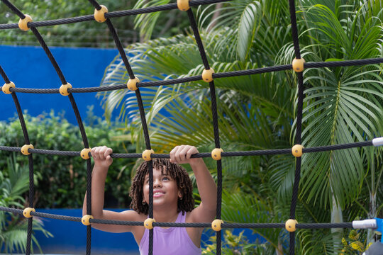 Happy smiling girl climbing playground rope net