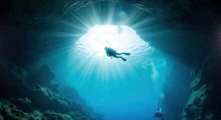 Two divers explore a dramatic sunlit underwater cave with bright rays and clear blue water