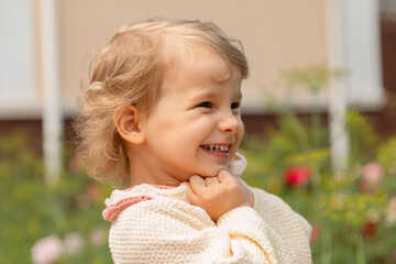Smiling toddler enjoying a sunny day outdoors, captured in a warm and joyful close-up. Natural light, genuine emotion, and a soft garden background.