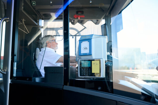 Senior bus driver operating public transport with ticket machine - Powered by Adobe