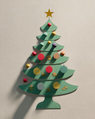 Christmas tree decoration with colorful ornaments and star on top casting shadows on wall