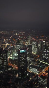 Vertical aerial view of illuminated Frankfurt am Main skyline at night. Trianon and other skyscrapers and office buildings light up urban landscape
