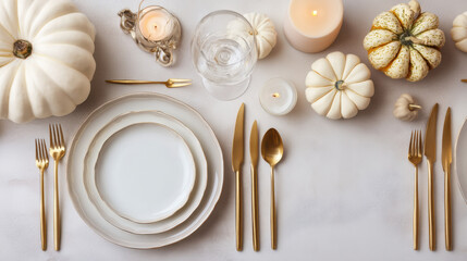 White pumpkin autumn table setting with gold cutlery and candles on white tablecloth for festive dinner