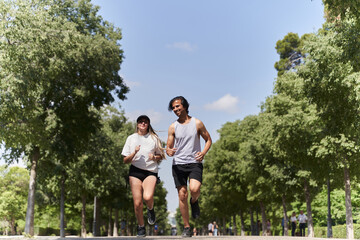 Happy couple running in city park during summer day