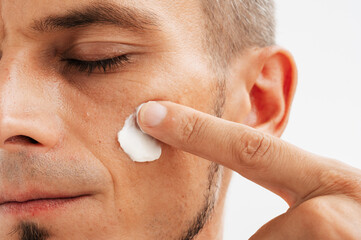 Portrait of a man with a cosmetic cream on his cheek.