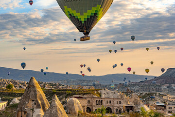 Goreme, Turkey - 19 April 2025: Aerial view of a sky filled with hot air balloons floating over the surreal landscape of Cappadocia's fairy chimneys.