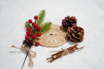 Natural Elements for Holiday Decoration Including Pine Cones, Berries, Greenery, and Rattan on Light Wood Background