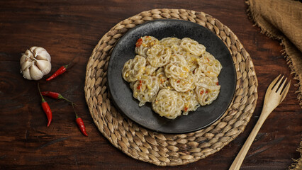 A plate of spicy seblak kerupuk, an Indonesian savory dish made from softened crackers with chili, garlic, and seasoning, served in a rustic setting.