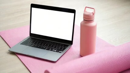 Home workout setting with blank laptop screen, pink exercise mat, and water bottle, digital fitness application, online training programs, fitness product promotion, exercise blog, fitness platform