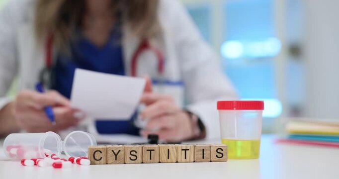 Wooden blocks spell word Cystitis near urine sample container and capsules on table. Woman urologist reads result writing note about bladder problem