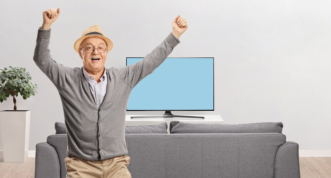 Happy elderly man with arms up in a room