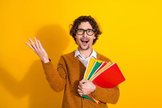 Happy stylish young man with glasses holds colorful notebooks against a yellow background for advertising shopping lifestyle stock photo