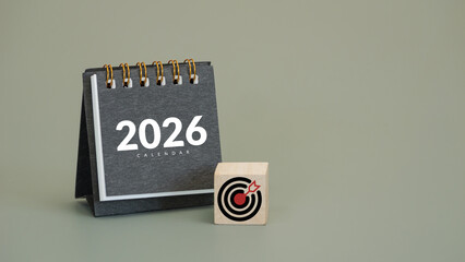 black desk calendar year 2026 with target icon on wooden cubes with copy space, symbolizing goals...
