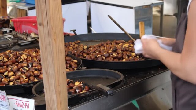 Woman cooking nuts in large pans for commercial distribution