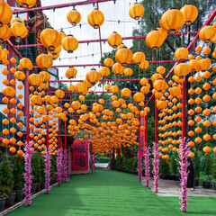 Hundreds of orange lanterns and pink cherry blossoms adorn the pathway at Thean Hou Temple, Kuala Lumpur, Malaysia, creating a vibrant scene.
