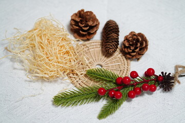 Natural Elements for Holiday Decorations Featuring Pinecones, Red Berries, Straw, and Greenery on a White Tablecloth Background