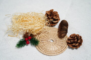 Natural Rustic Decor Elements with Pine Cones, Straw, Holiday Berries, and Rattan Mat on Textured White Background for Seasonal Arrangement Ideas